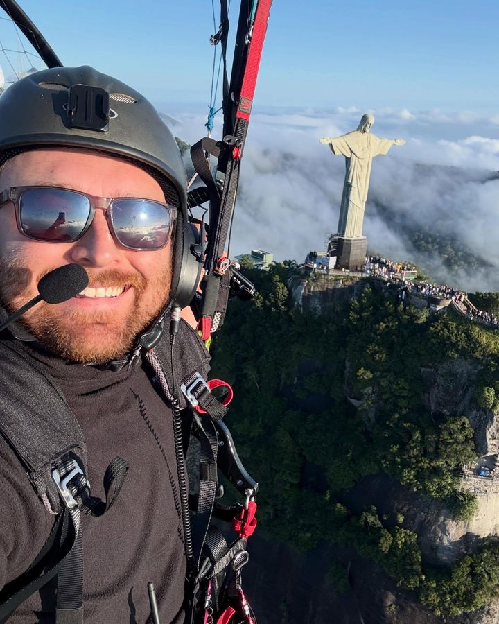 Alex Lang flying a paramotor past Christ the Redeemer above the clouds in Rio de Janeiro